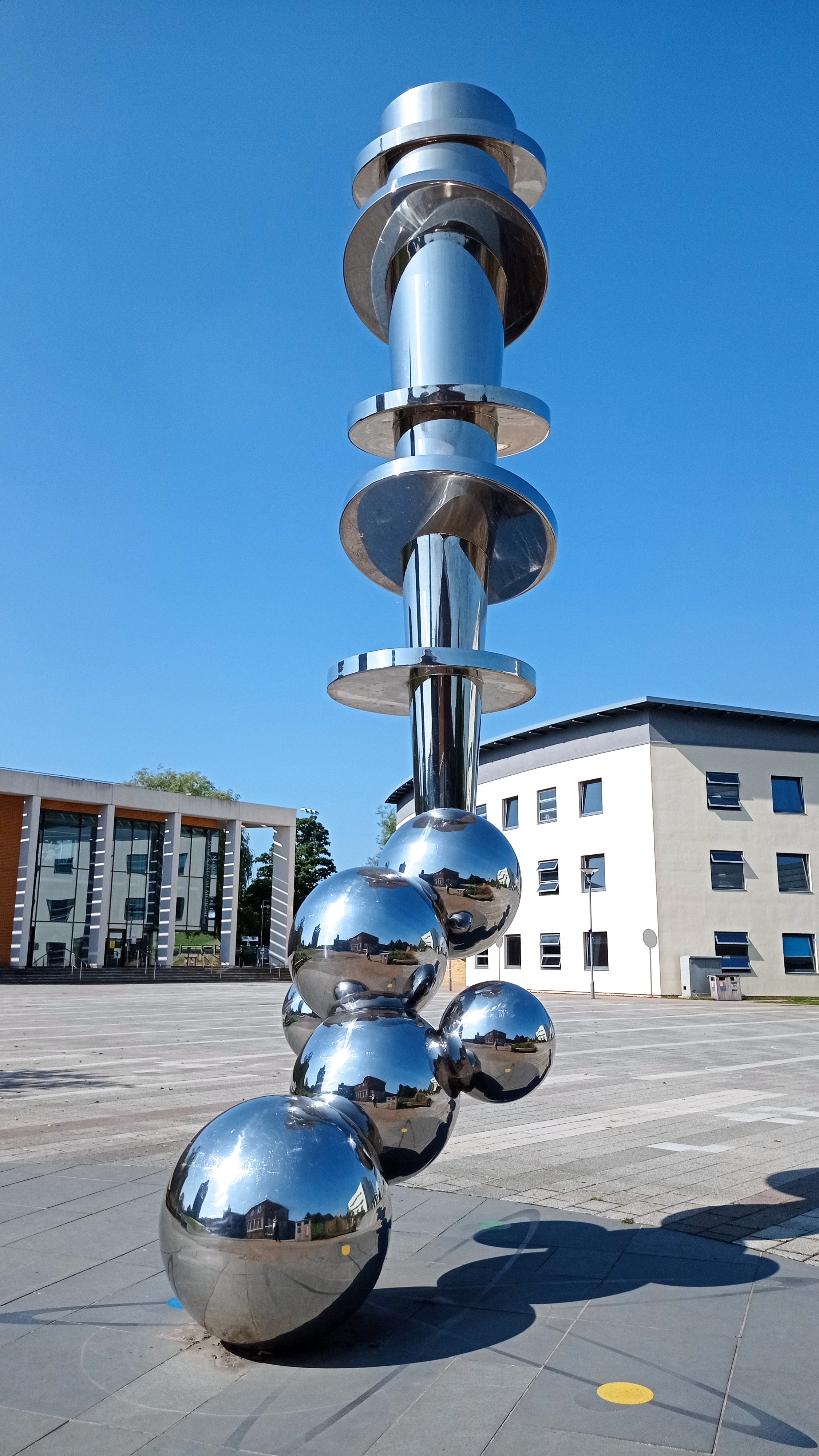 Tall abstract stainless steel sculpture with spherical forms combining to make a column